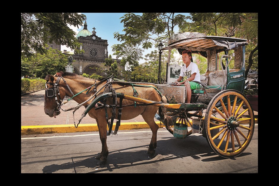 HORSE-DRAWN CARRIAGES OUTSIDE MANILA CATHEDRAL OFFER TOURS OF INTRAMUROS